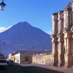 VISTA DESDE UNA CALLE DE ANTIGUA GUATEMALA DONDE SE APRECIA EL VOLCAN DE AGUA Y PARTE DE LA FACHADA DE USA IGLESIA QUE SE LLAMA DEL CARMEN